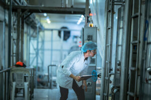 Industrial worker inspecting production machinery in a modern food processing facility.