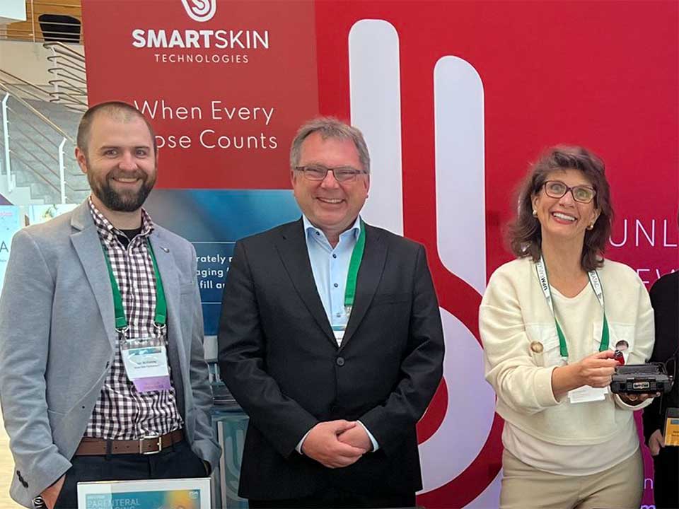 SmartSkin team standing in front of red SmartSkin banner